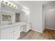 Bathroom featuring double sinks, a large mirror with vanity lighting, and wood look floors at 3920 Cain Mill Dr, Lithonia, GA 30038