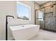 Freestanding tub and glass enclosed shower in remodeled bathroom with black fixtures and tile walls at 482 Majestic Oaks Pl, Smyrna, GA 30082