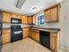 Cozy kitchen featuring maple cabinets and black appliances, with a large window over the sink at 1005 Magnolia Gardens Walk, Mcdonough, GA 30253