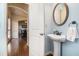 Charming powder room with a pedestal sink, oval mirror, and view to a dining room beyond an arched entrance at 307 Montgomery Way, Woodstock, GA 30188