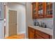 Charming butler's pantry featuring granite countertops and custom cabinets with glass doors and warm lighting at 12800 Wyngate Trl, Alpharetta, GA 30005