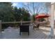 Large wooden deck features a sitting area with a red umbrella and wooded views at 12800 Wyngate Trl, Alpharetta, GA 30005