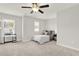 Neutral bedroom with a ceiling fan, carpet flooring, two windows, and a console table under the window at 2128 Cosette Ln, Kennesaw, GA 30152