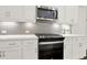 Close-up showcases the kitchen's modern stove, microwave, white cabinets, stainless steel hardware, and tiled backsplash at 2128 Cosette Ln, Kennesaw, GA 30152