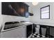 Modern laundry room features front load washer/dryer, black cabinets, and black and white tile flooring at 835 Kenry Ct, Atlanta, GA 30342