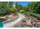 Exciting backyard waterslide integrated into the natural rock landscape, leading to a sparkling pool at 1391 Harris Rd, Lawrenceville, GA 30043