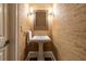 Small powder room featuring textured wallpaper, pedestal sink, framed mirror, and sconce lighting at 4022 Newhaven Ne Cir, Brookhaven, GA 30319