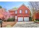 Two-story brick home with a two-car garage and a paved driveway, complemented by lush landscaping and blossoming trees at 1926 Regency Cove Ct, Atlanta, GA 30341