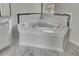 Close up of garden tub in primary bathroom with tiled surround and floors at 3635 Spring Mesa Dr, Snellville, GA 30039