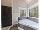 Bathroom showcasing tiled tub with large windows providing natural light and views at 6490 Lake Esther Dr, Fairburn, GA 30213