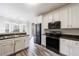 Open kitchen with white cabinetry, wood-look floors, stainless steel appliances, and black countertops at 6490 Lake Esther Dr, Fairburn, GA 30213