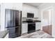 Bright kitchen with white cabinetry, wood-look floors, stainless steel appliances, and black countertops at 6490 Lake Esther Dr, Fairburn, GA 30213