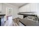 Bright kitchen with white cabinetry, wood-look floors, stainless steel appliances, and black countertops at 6490 Lake Esther Dr, Fairburn, GA 30213
