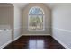 Bright living room with dark wood floors, arched window, and neutral wall paint at 6490 Lake Esther Dr, Fairburn, GA 30213
