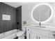 Modern bathroom featuring a herringbone tile accent wall and a vanity with a round, backlit mirror at 1194 Clearview Ne Dr, Brookhaven, GA 30319