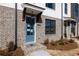 Townhome showcasing a blue door, brick exterior, small porch, and neatly arranged landscaping at 1132 Larkin Dr # 34, Buford, GA 30518