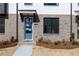 Close-up of townhome featuring blue door, brick facade, covered porch, and manicured landscaping at 1132 Larkin Dr # 34, Buford, GA 30518