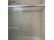 Close-up of a shower stall featuring frosted sliding glass doors and neutral-toned marbled tile at 6308 Boyett Drive Dr, Norcross, GA 30093