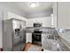 Well-lit kitchen features stainless steel appliances, granite countertops, white cabinetry, and a stylish backsplash at 1780 Brookside Lay Cir, Norcross, GA 30093