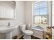 Modern half-bath with pedestal sink, toilet, and window bringing in natural light at 3567 Hidden Valley Cir, Lawrenceville, GA 30044