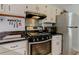 A kitchen with a stainless-steel oven and overhead vent, white cabinets, black countertops, and a stainless-steel refrigerator at 403 Oak Harbor Ct, Marietta, GA 30066