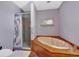 Bathroom features an oval tub with wood paneling and a separate shower with glass door and purple floral curtain at 4565 Canebrake Ct, Powder Springs, GA 30127