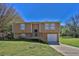 Split-level home featuring a front porch, attached garage and well-maintained lawn under a sunny blue sky at 5219 Sweet Air Ln, Stone Mountain, GA 30088