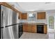 Kitchen boasts stainless steel refrigerator, oak cabinets, black appliances, and a window for natural light at 5219 Sweet Air Ln, Stone Mountain, GA 30088