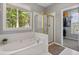 Bright bathroom features a soaking tub beneath a large window and a glass-enclosed shower at 3545 Silver Vista Ct, Cumming, GA 30041