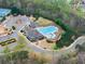 Aerial view of community amenities showcasing a pool, clubhouse, tennis courts, and playground nestled in a wooded area at 6635 Canyon Cv, Cumming, GA 30028