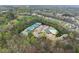 Aerial view of community amenities showcasing a pool, tennis courts, playground, and clubhouse surrounded by lush greenery at 6635 Canyon Cv, Cumming, GA 30028