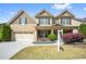 Charming two-story home featuring a manicured front lawn, attached garage, and traditional architectural details at 2195 Well Springs Dr, Buford, GA 30519