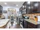 View of kitchen features stainless steel appliances, granite countertops, and dark brown cabinetry with view of dining room at 2195 Well Springs Dr, Buford, GA 30519