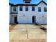 Charming townhome featuring a white brick facade, black-trimmed windows, and convenient two-car garages at 36 S Auburn Landing Pl, Auburn, GA 30011