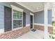 Inviting front porch featuring brick accents, white pillars, black door, and view of the well-maintained lawn and landscaping at 9061 Jim Purcell Dr, Covington, GA 30014