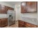 Stainless refrigerator surrounded by granite countertops and wood cabinets at 9061 Jim Purcell Dr, Covington, GA 30014