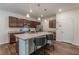 Open kitchen with island, granite counters, stainless appliances, pendant lighting, and rich wood cabinets at 9061 Jim Purcell Dr, Covington, GA 30014
