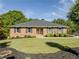 Charming brick home featuring a lush front lawn with mature trees and landscaped garden beds at 458 Valley Woods Se Cir, Conyers, GA 30094