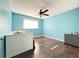 Blue bedroom featuring hardwood floors, ceiling fan, and a crib next to a window at 2563 Hamill Dr, Buford, GA 30519