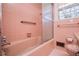 Retro pink bathroom features a tiled shower over tub, grab bar, and window at 1181 Angelia Sw Dr, Mableton, GA 30126