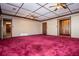 Spacious living room with red carpet, paneled ceiling, and unique wooden door at 1181 Angelia Sw Dr, Mableton, GA 30126