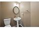 Cozy half-bath with a pedestal sink, decorative mirror, and neutral color scheme at 3940 Medlock Park Dr, Snellville, GA 30039