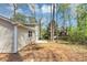 View of home's backyard and side exterior, featuring a compact patio and lush trees in background at 5307 Mountain Village Ct, Stone Mountain, GA 30083
