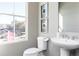 Modern half-bathroom with a pedestal sink, toilet, and window providing natural light at 335 Skylar Se Way, Atlanta, GA 30315