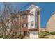 Charming two-story townhome featuring a brick facade, attached garage, and manicured landscaping under a clear blue sky at 2164 Mill Garden Run, Buford, GA 30519