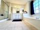 Bright bathroom featuring a tub, shower, double vanity, and a large mirror at 4722 Bradford Ln, Powder Springs, GA 30127