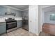 Galley kitchen features gray cabinets, stainless steel appliances, tile floor, and access to another room at 5030 Sumit Wood Dr, Kennesaw, GA 30152