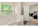 This bathroom features a large window, tiled floors, a large tub and a view into the main bedroom at 1395 Brisbane Dr, Dacula, GA 30019