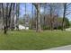 A serene yard showcasing a lush green lawn, mature trees, and a quaint house in the background at 5720 Crow Dr, Cumming, GA 30041