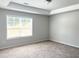 Neutral bedroom with large window, carpet, and tray ceiling at 258 Station Overlook Dr, Auburn, GA 30011